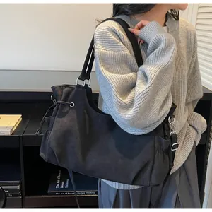 Detalle de bolso tote negro con correa ajustable y cordón decorativo mostrado en modelo