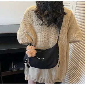 Vue détaillée du sac bandoulière noir avec pendentif ours et bandoulière à logo