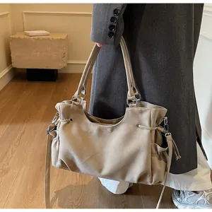 Detalle de bolso tote beige con cordón ajustable, bolsillo lateral y bandolera