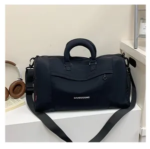 Detail of black oxford cloth travel bag showing reinforced handles and adjustable strap