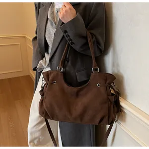 Detalle de bolso tote de ante marrón oscuro con cordones ajustables y hebillas metálicas