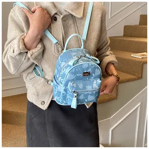 Close-up of blue floral mini backpack featuring silver zippers and leather trim details