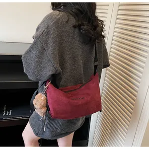 Détail du sac bandoulière en daim bordeaux avec imprimé lettres et pendentif ours brun
