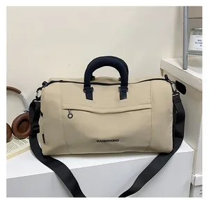 Close-up of beige travel bag with black handles, adjustable strap and front zipper pocket