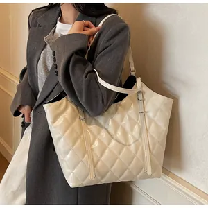 Chic cream quilted tote bag with glossy finish and silver buckle on female model