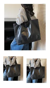 Detail of a large black canvas tote bag featuring textured logo and long woven shoulder straps