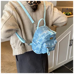 Back view of a woman wearing a light blue floral mini backpack in a cozy indoor setting