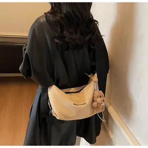 Gros plan du sac demi-lune beige orné d'un joli porte-clés en peluche de chiot marron