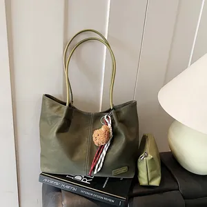 Olive green faux leather tote bag set with bear charm and small pouch on leather seat