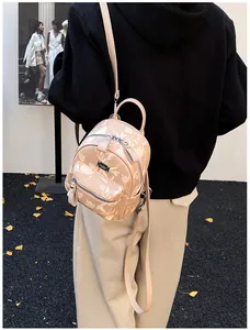 Close-up of beige mini floral backpack with silver zippers and adjustable straps on model