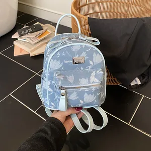 Mini light blue denim backpack with white floral patterns and silver logo plate