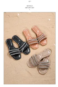 Nahaufnahme von Bohemian-Sandalen mit Strassriemen auf natürlichem Sandstrand-Hintergrund