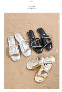 Sandalias bohemias planas en plata negro y oro con pedrería sobre un fondo de playa de arena