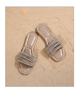Detail von böhmischen flachen Sandalen mit glitzernden Strasssteinen auf Sandhintergrund