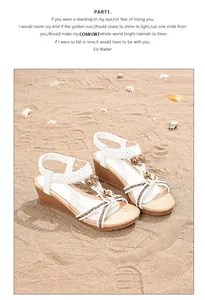 Détail de sandales compensées blanches bohèmes avec perles et fleurs sur la plage