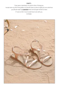 Detail of bohemian flat sandals featuring braided straps and buckle on sandy beach