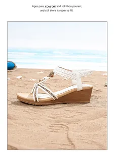 Détail de sandales compensées blanches bohèmes avec brides tressées et bijoux sur la plage