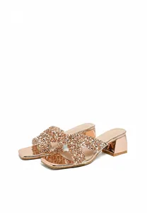 Close-up of rose gold platform sandals featuring rhinestone crisscross straps and square toe