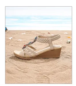 Detail of bohemian wedge sandals with colorful gemstones on beach sand background
