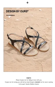 Close-up of bohemian flat sandals with black woven straps on a sandy beach setting