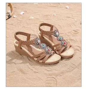 Close-up of Bohemian wedge sandals with colorful ethnic rhinestones on a sandy beach