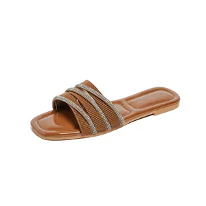Böhmische flache Sandalen in Braun mit Strass-Kreuzriemen auf weißem Hintergrund