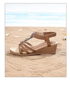 Detail of bohemian wedge sandals with colorful beads and braided straps on beach sand