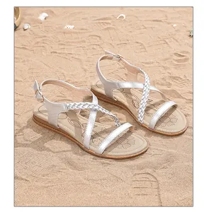 Silver Bohemian flat sandals with woven straps on a summer beach background