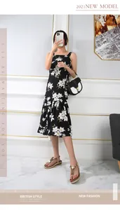 Detail of floral bohemian summer sandals paired with a black square-neck lily print dress