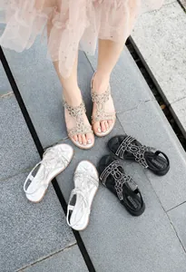 Detailed outdoor shot of rhinestone flat sandals in champagne, silver, and black colors