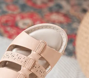 Detail van roze sandalen van zacht kunstleer met opengewerkt design en nauwkeurige stiksels