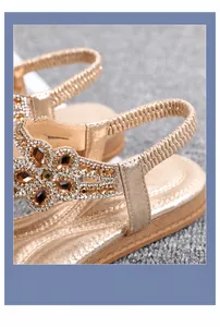 Close-up of bohemian sandals featuring rhinestone flowers and elastic heel strap detail