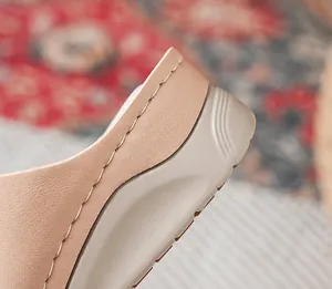 Detail van handgestikte stiksels op beige sleehak sandalen met dikke platformzolen
