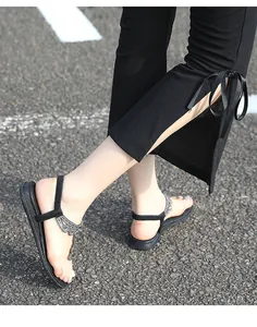 Gros plan de sandales bohèmes noires avec strass et pantalon orné de nœuds en ruban élégants