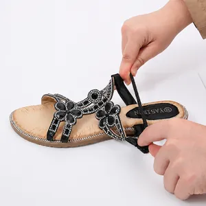 Détail de la bride élastique au talon sur sandales noires à strass pour un enfilage facile
