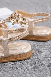 Close-up of non-slip TPR rubber sole on bohemian flat sandals with rhinestone floral detail