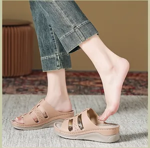 Detail van beige sleehak sandalen met lasergesneden bandjes en stiksels aan de zijkant