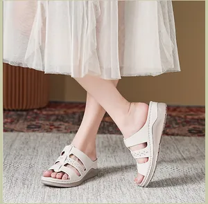 Detailopname van beige sandalen met sleehak, decoratieve uitsparingen en een comfortabele zool