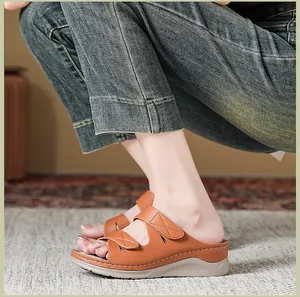 Detalle de sandalias de cuña marrón con tiras de pespunte y suelas blancas gruesas de goma