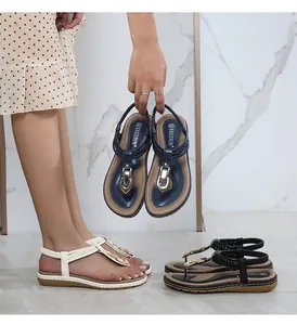 Detail of T-strap thong sandals with gold buckles and woven leather details for women