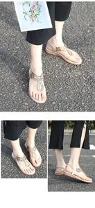Detailansicht champagnergoldener flacher Sandalen mit Strassblumen und böhmischem T-Riemen-Stil