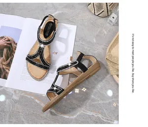 Dettaglio di sandali neri con cinturino a T e strass accanto ad accessori moda