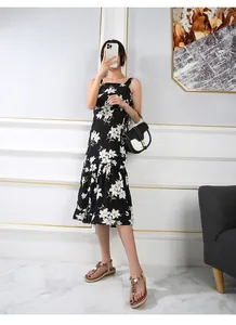 Detail of floral black midi dress with white lily print and ruffled hem for summer