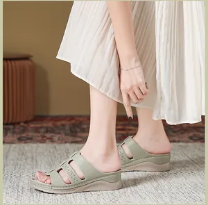 Detail van lichtgroene sleehak sandalen met drie bandjes en fijne lasergesneden patronen