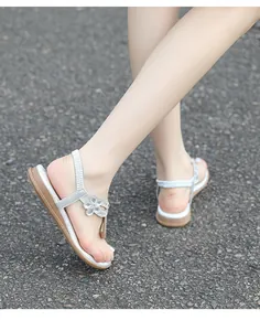 Details der silbernen Strass-Sandalen mit Blumenanhängern und elastischem Fersenriemen