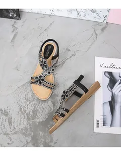 Détail de sandales plates noires pour femmes avec motifs floraux en strass et bride élastique