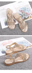 Detail of golden bohemian flat sandals with sparkling rhinestone flowers and elastic back strap