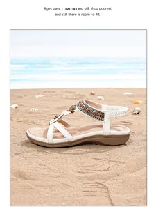 Détail de sandales compensées blanches avec perles bohèmes et anneau métallique à la plage
