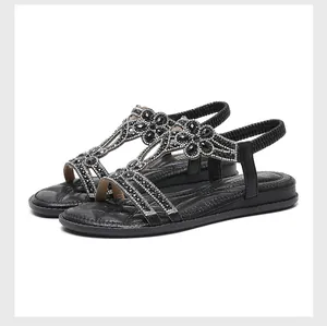 Detail of bohemian flat sandals featuring rhinestone flower patterns and T-strap design