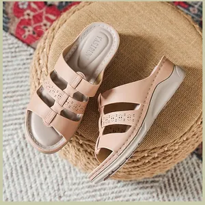 Detail van lasergesneden bloemmotieven op beige sleehak sandalen op een krukje